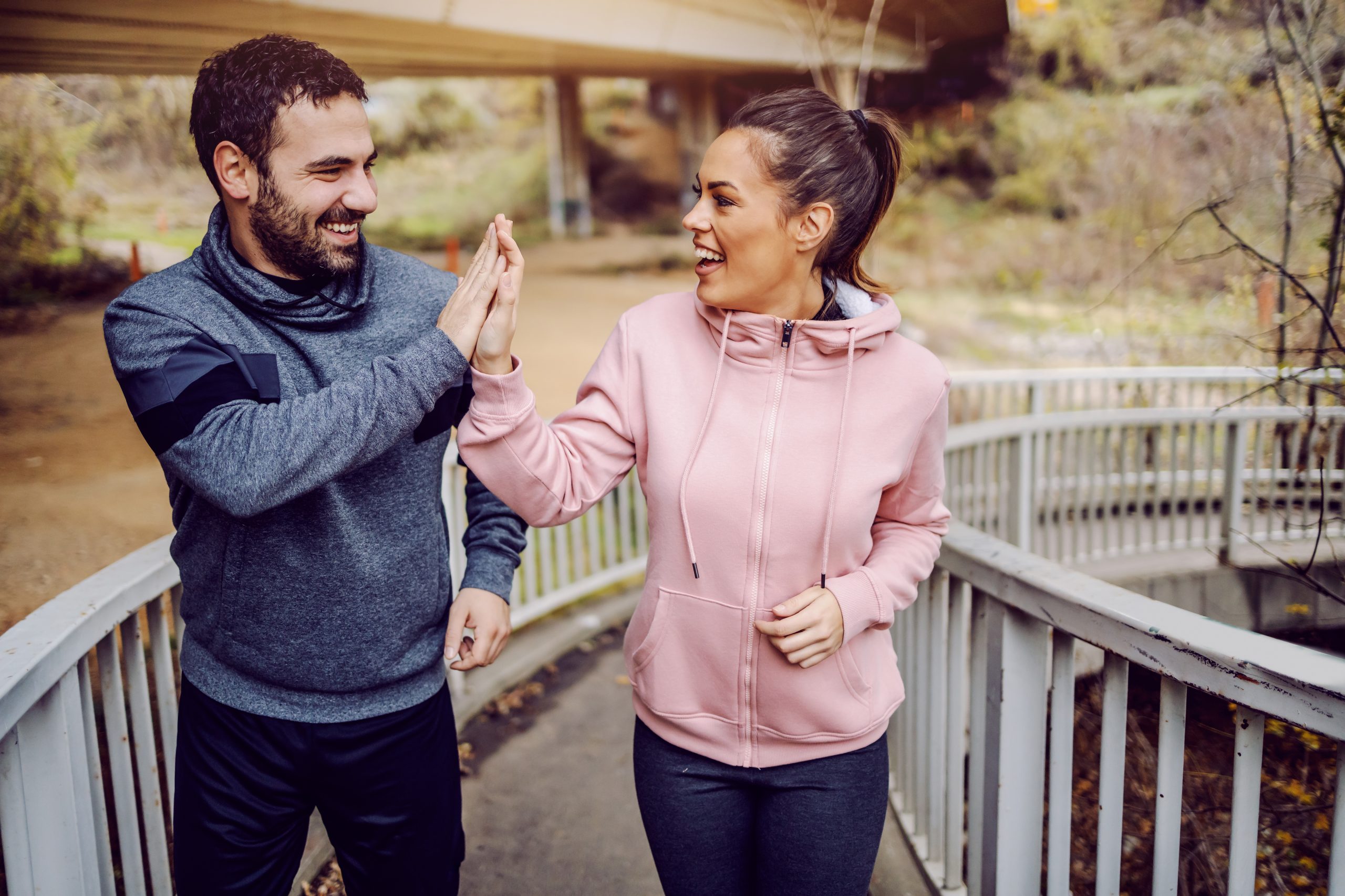 Gesunde junge Freunde, die über eine Brücke gehen und sich gegenseitig ein High Five geben.