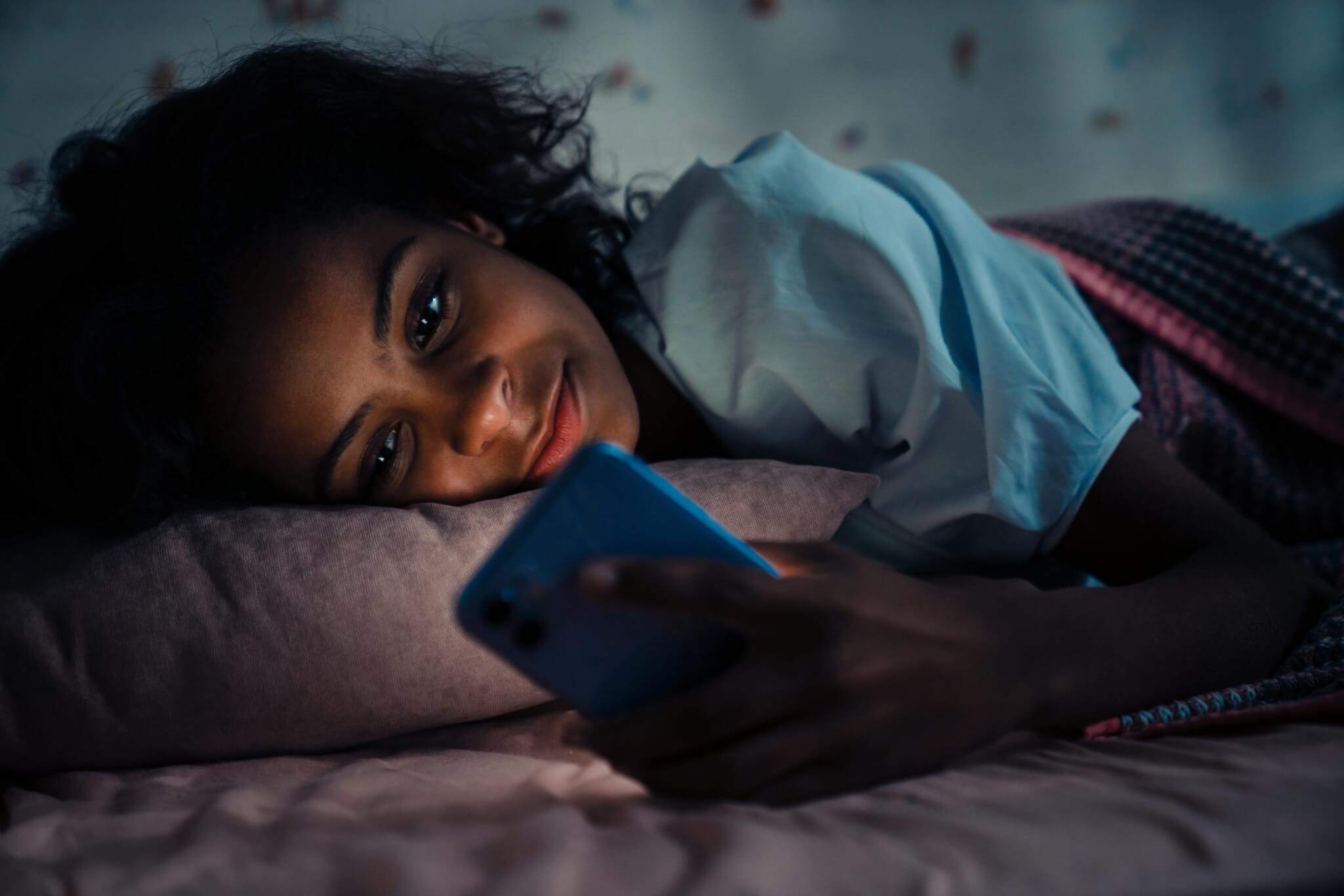Girl reading phone before bed blue light